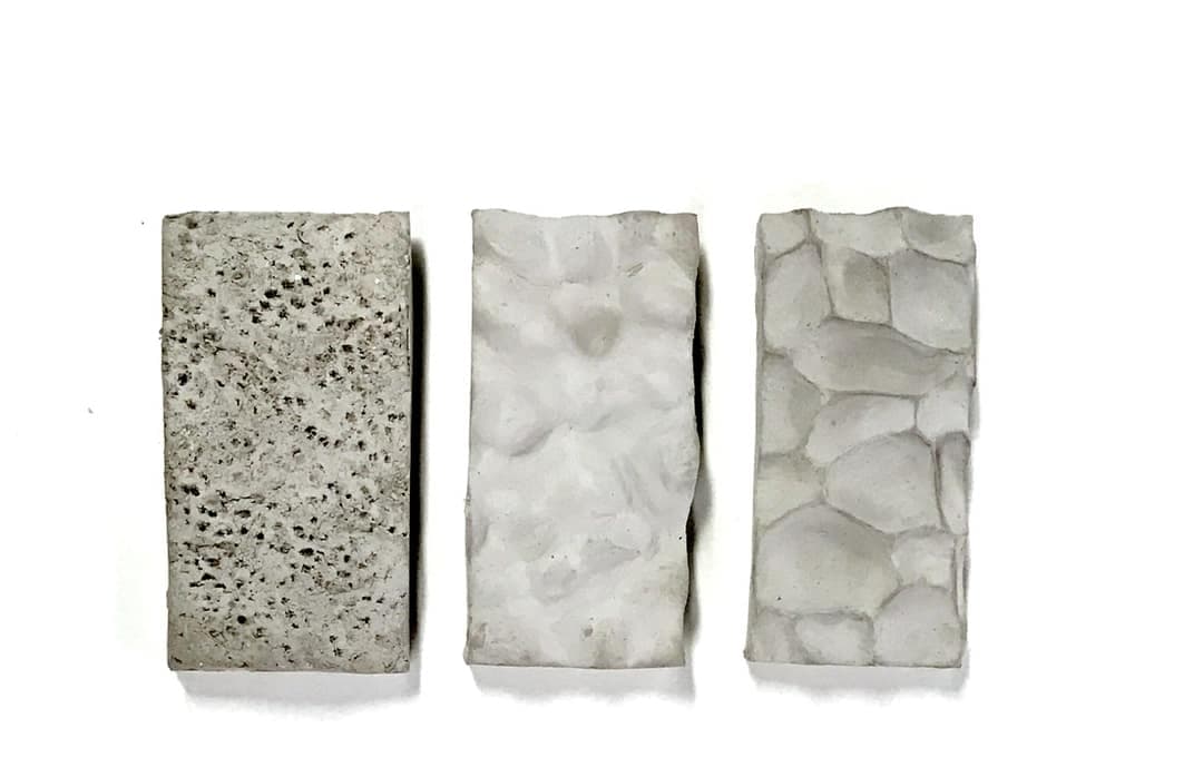 Three cast concrete samples with porous, rippled and cobbled surface textures